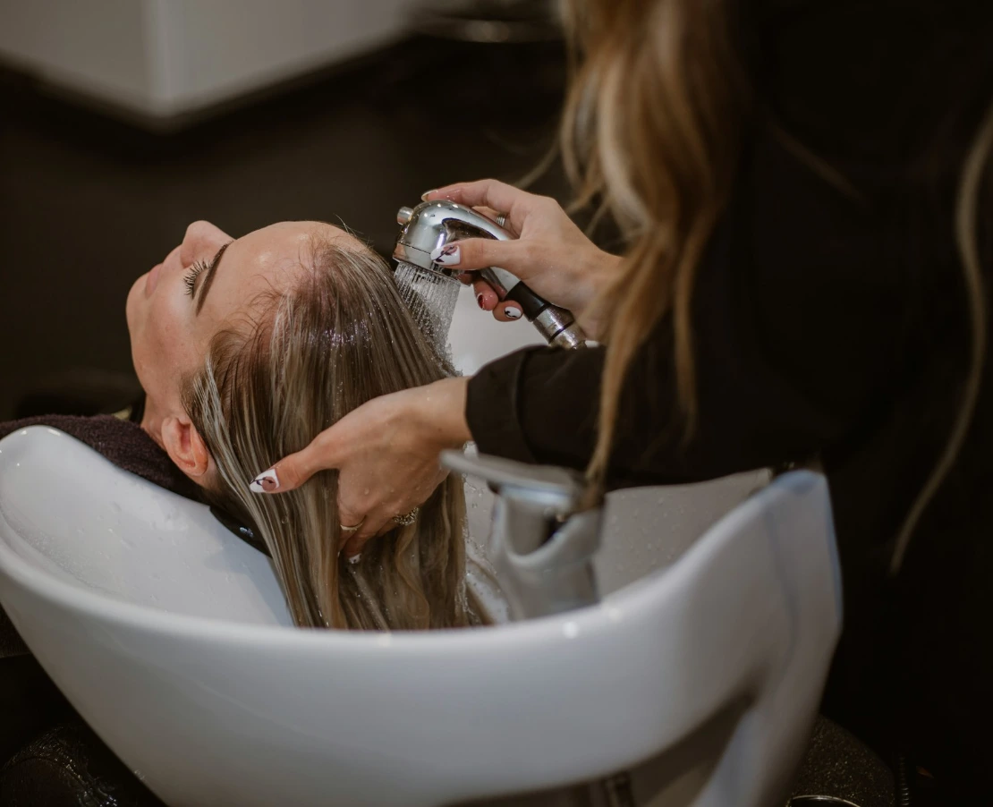 a woman getting her hair cut by a hair stylist
